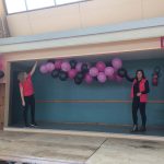 Julie et Fabienne accrochent la guirlande de ballons aux couleurs du label Vosges terre textile